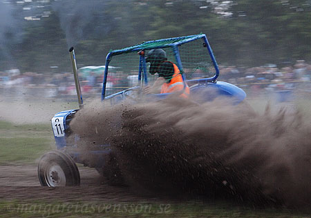 Det sprutar jord runt en blå traktor.